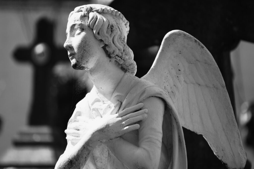 Black and white photo of a stone angel statue in a cemetery evoking peace.