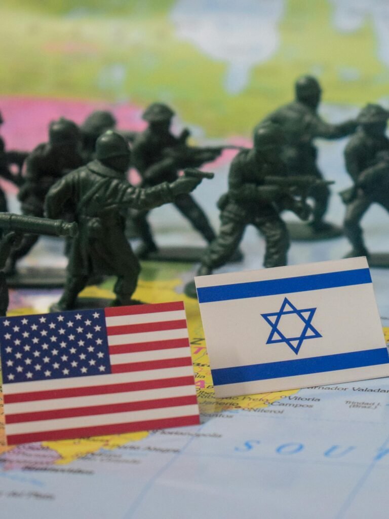 Miniature army figures with USA and Israel flags on a world map signifying military strategy.